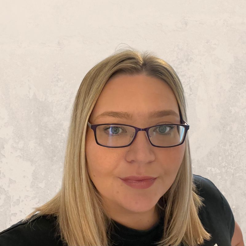 A woman with straight blonde hair, wearing dark-rimmed glasses and a black top, stands in front of a light gray textured background, ready to share top tips for avoiding digital impersonation and cyber fraud scams.